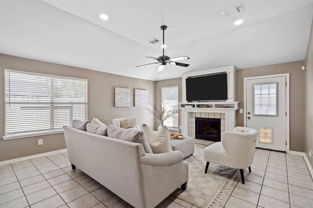 A wall of windows fills the family room with natural light, while a classic tile-surround fireplace adds warmth and charm to the space.