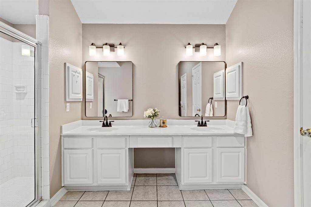The ensuite bath includes a generous dual sink vanity with updated lighting and a seated makeup station.