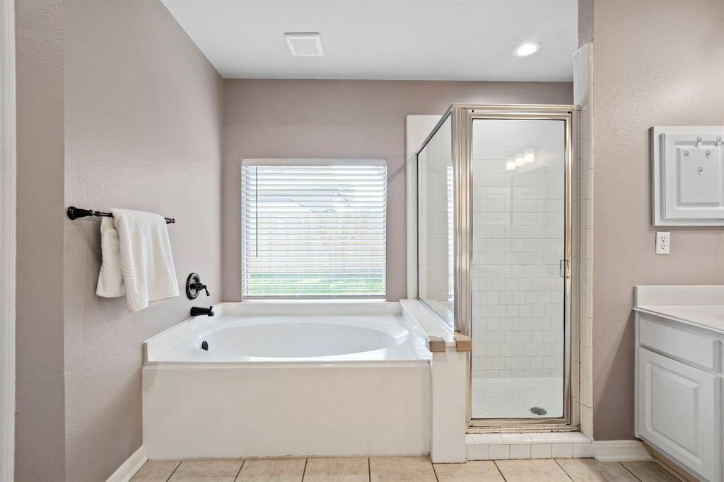 This inviting bath layout offers both a deep soaking tub and walk-in shower, creating a relaxing start or end to your day.