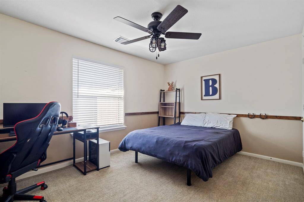 This spacious third bedroom features plush carpeting, a stylish ceiling fan, and a generous walk-in closet for ample storage space.