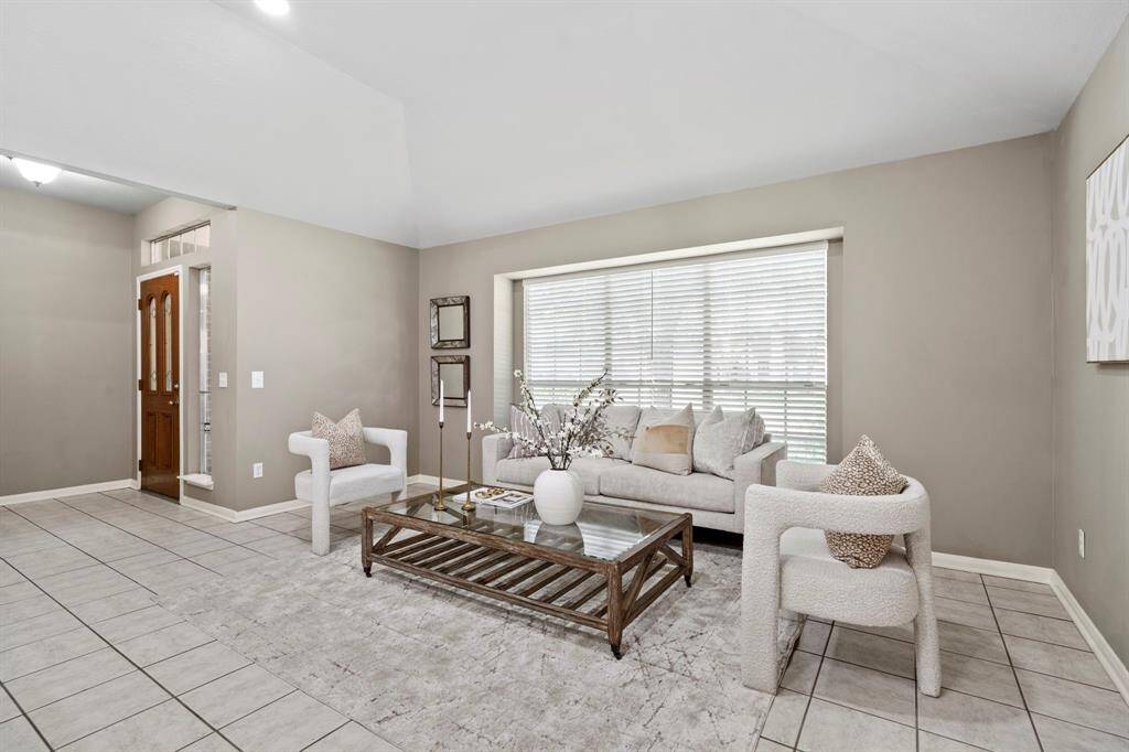 The formal living room sits just off the entry, featuring soaring ceilings, neutral paint, and tile flooring for a clean, spacious feel.