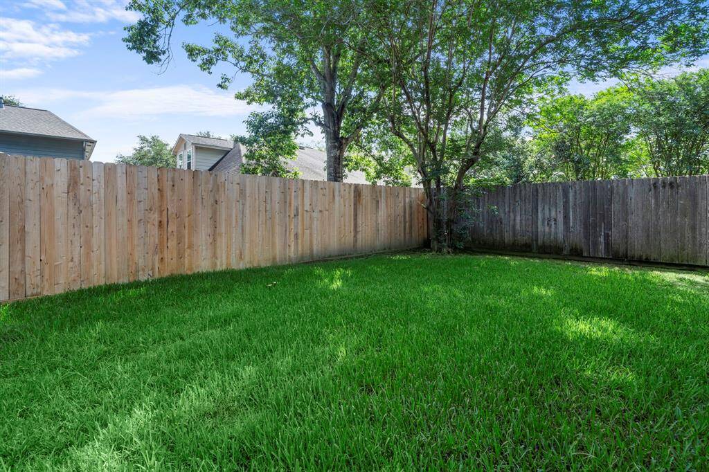 The lush, fenced backyard provides plenty of room to run, play, or enjoy quiet afternoons under the shade of mature trees.
