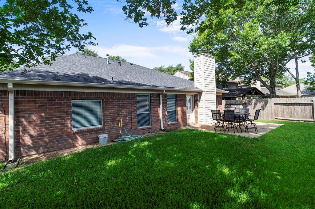 A view of the home’s charming brick exterior and extended patio highlights the generous outdoor space perfect for gatherings.