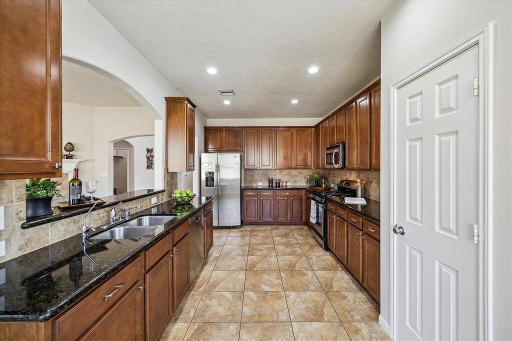 This kitchen offers a spacious layout with a double sink, modern lighting, and tile flooring, providing a plenty of space for cooking.