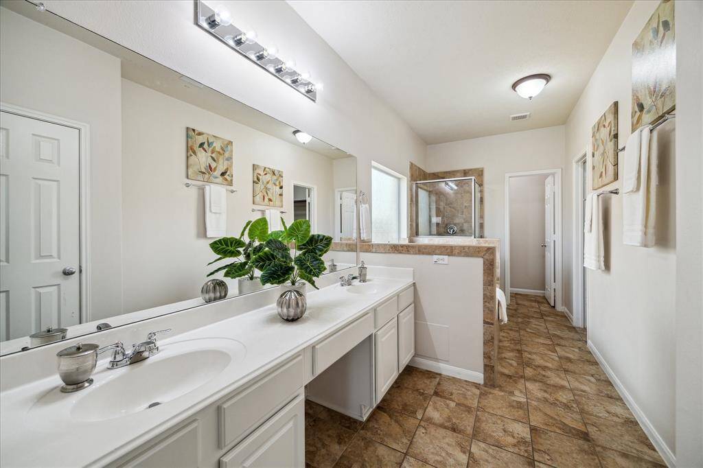 Luxurious primary ensuite bathroom featuring dual sinks, elegant tile flooring, and a spacious walk-in shower.