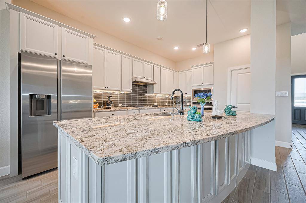 Oversized granite island with a deep sink and pendant lighting, ideal for prepping meals or casual dining—centrally located in this open-concept layout.