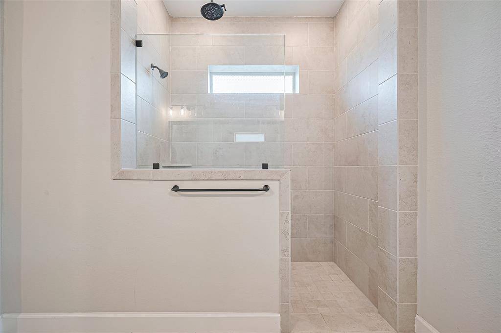 The walk-in shower with tile surround and rain showerhead offers a serene retreat, while the spacious layout connects seamlessly to the primary suite