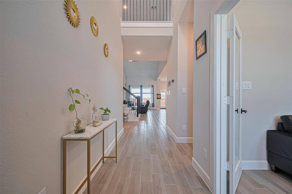 Welcoming entryway with high ceilings, wood-look tile flooring, and elegant wall accents creating a warm and inviting first impression.