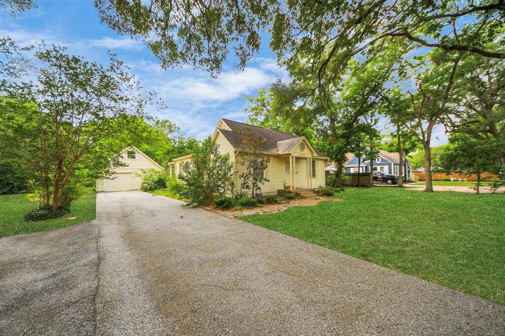 A long driveway runs alongside the home, with additional parking space, leading to a detached garage. The expansive layout offers room for guests, projects, or play.