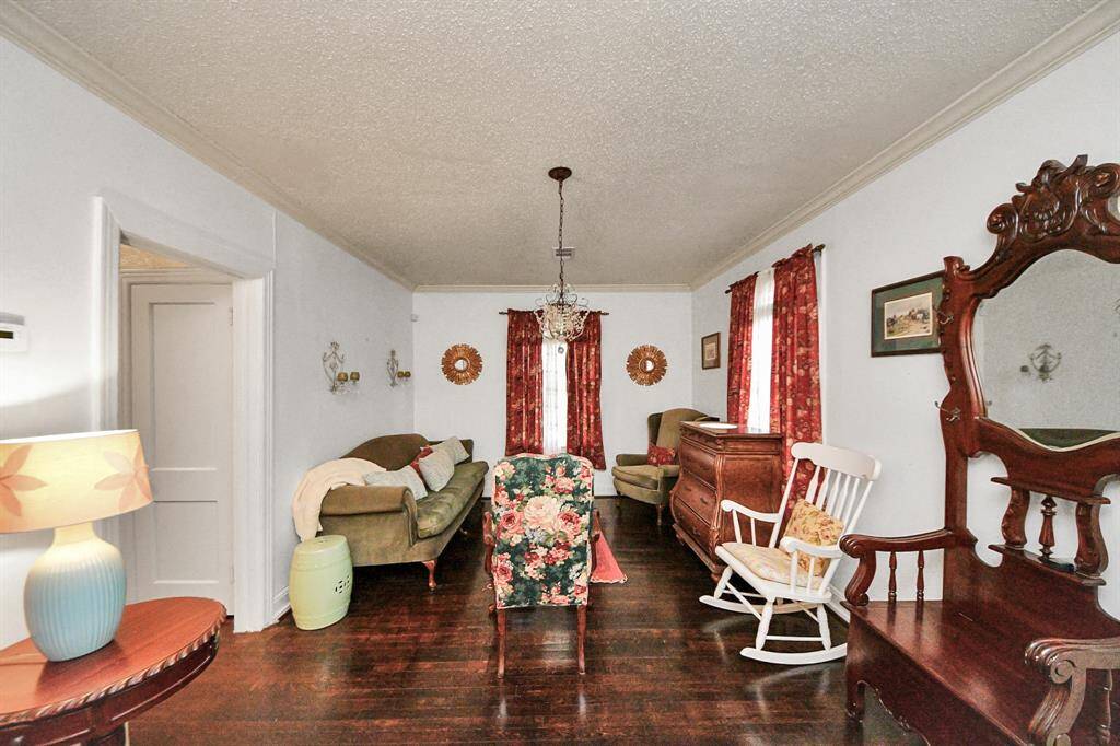 The den offers a cozy gathering space with original wood floors, crown molding, and vintage charm. Natural light filters through two classic rope-and-pulley windows, adding to the warmth of this inviting room.