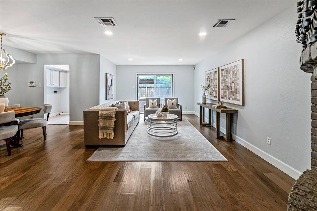 The inviting living space features sleek wood floors, a cozy seating area abundant natural light through a large sliding glass door. The simple, tasteful color scheme enhances the contemporary feel.
