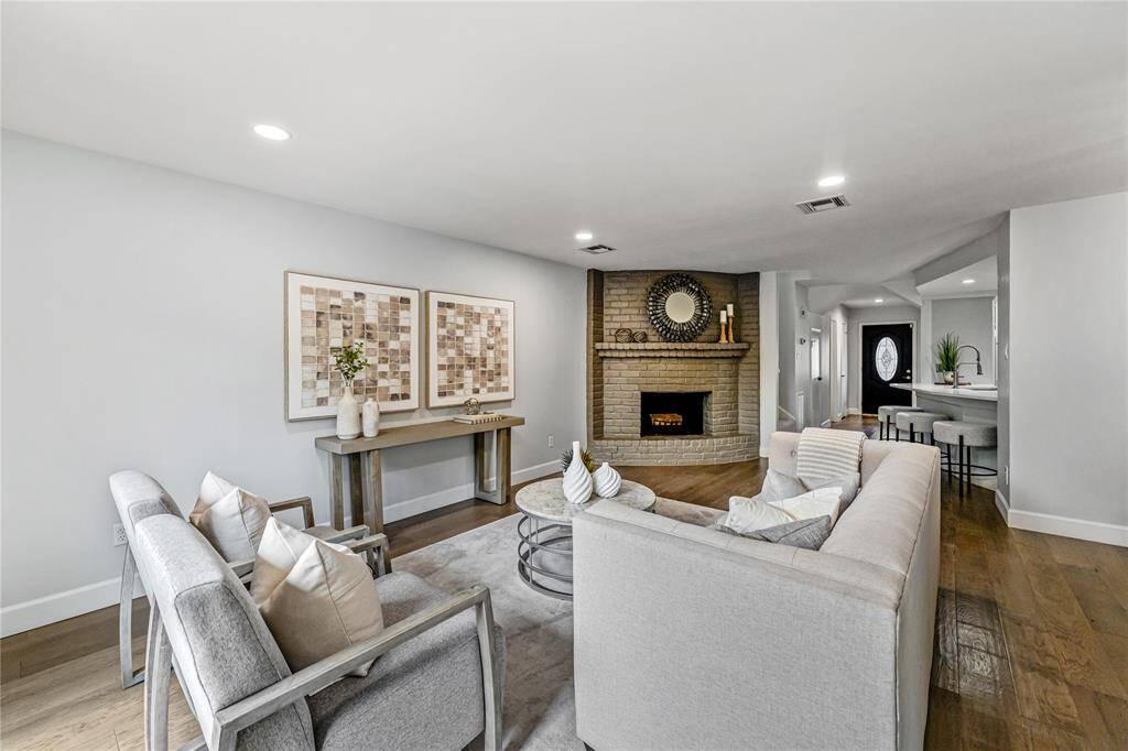 Another view of the living room, offering a cozy, open layout with a stylish brick fireplace. It seamlessly connects to the dining area and kitchen, creating an inviting space for relaxation and entertaining.