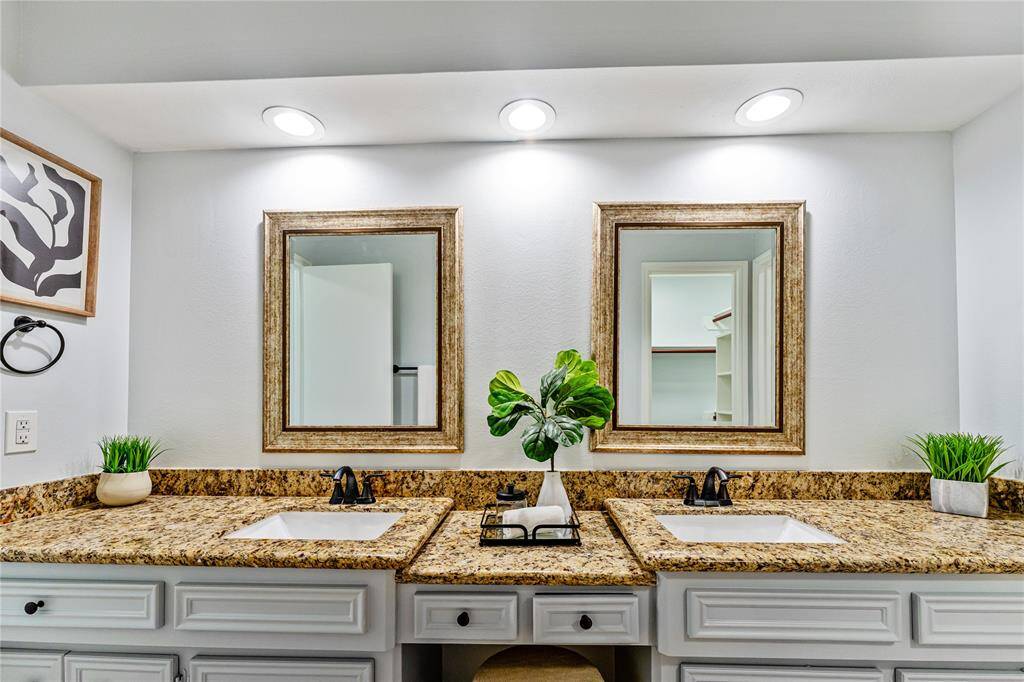 The main ensuite bathroom features a double vanity with granite countertops, dual sinks, and elegant framed mirrors. Recessed lighting highlights the space.