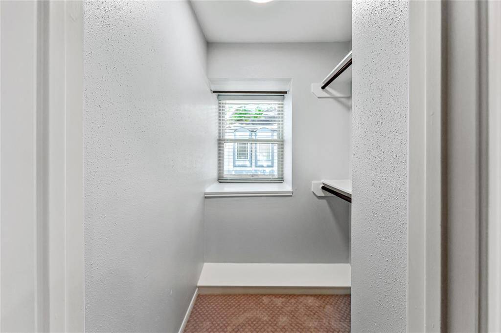 The main bedroom has two  walk-in closets. This light-filled closet features a window to the front and a shelf for shoes.