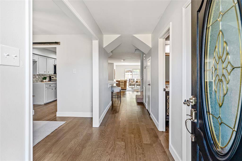 Inviting entryway with wood floors leading to a bright, open living area straight ahead, creating a welcoming and functional layout.