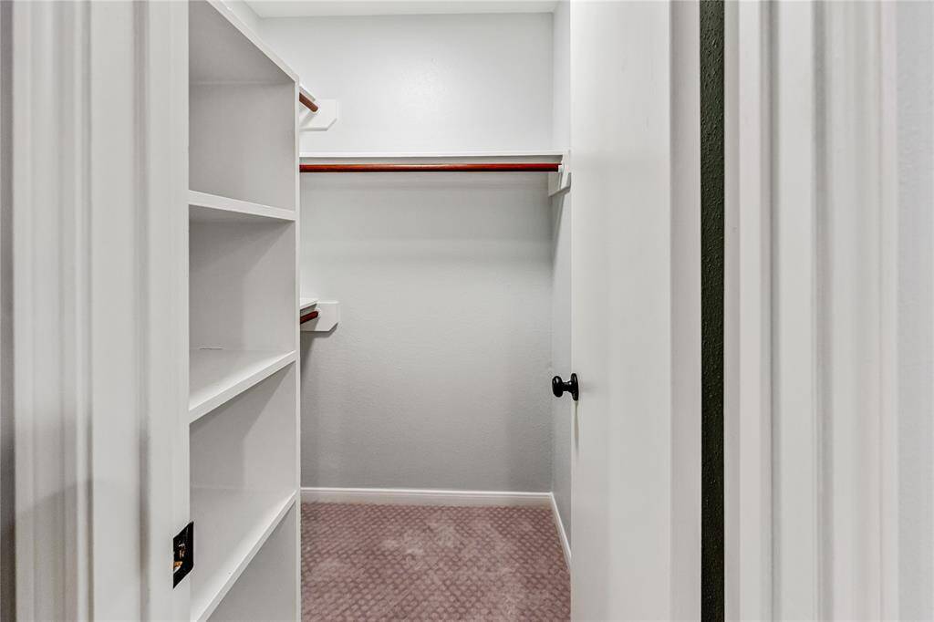 Second walk-in closet with built-in shelving creates a clean and organized space.