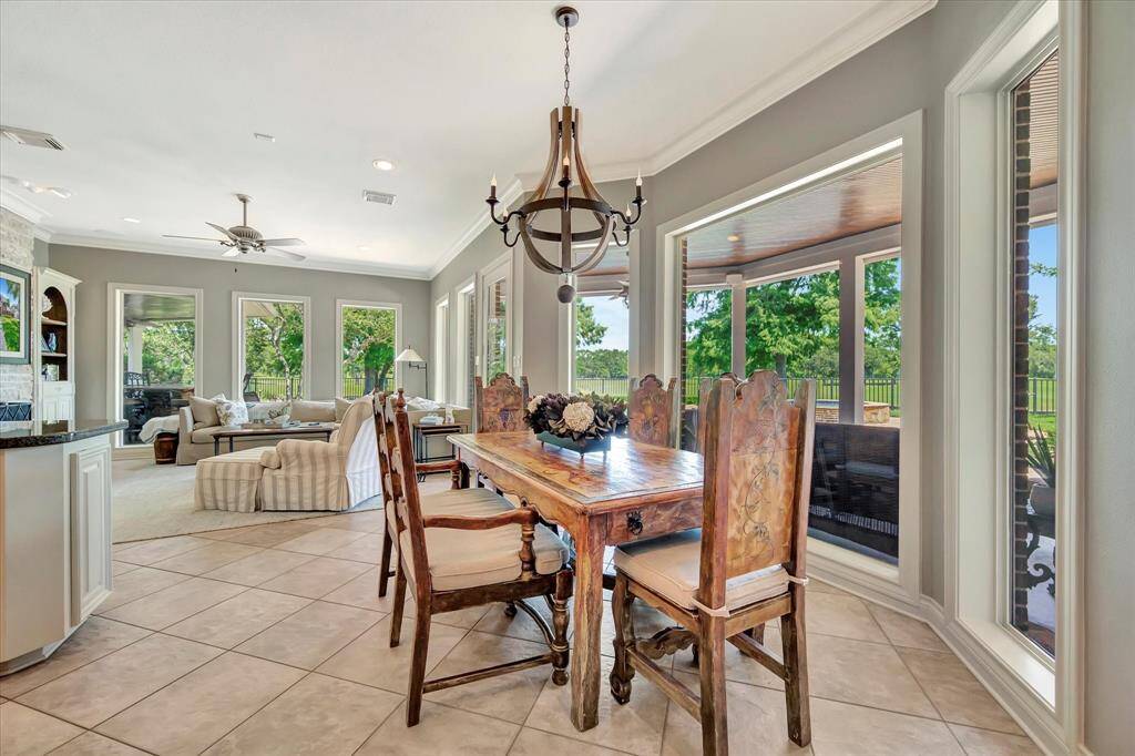 Secondary dining area/breakfast nook with custom chandelier, walls of windows creating natural flow from kitchen and den.