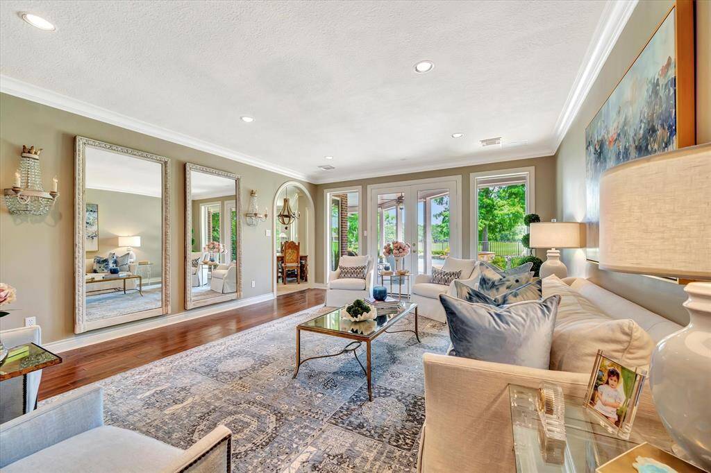 This inviting living room features elegant decor with large ample natural light from multiple windows, and a seamless indoor-outdoor flow. It boasts hardwood floors, a cozy seating area, and tasteful accents, creating a welcoming atmosphere.