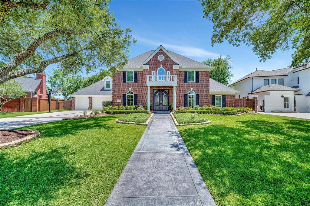 This inviting home features a classic brick exterior with a welcoming pathway leading to a grand entrance. The well-maintained lawn is accented by mature trees and manicured landscaping, offering excellent curb appeal. The property is set in a peaceful neighborhood with a spacious driveway for convenient parking.