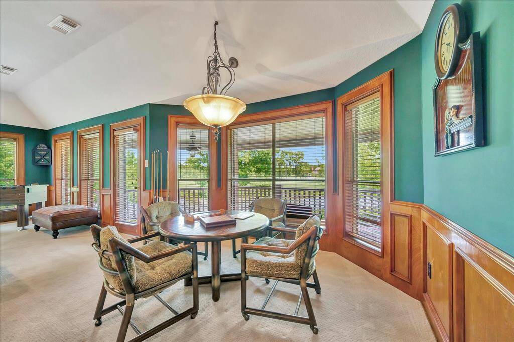 This photo showcases a cozy home bar area with granite countertops, wooden cabinetry, and stylish lighting. The space features a TV, decorative wall accents, and ample seating, perfect for entertaining.