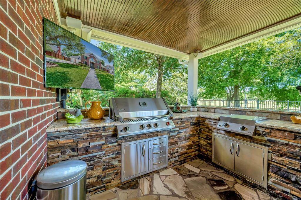 This photo showcases a beautiful backyard with a well-maintained lawn, a covered patio, and a brick outdoor bar area. It's perfect for entertaining, with lounge chairs by a pool and lush greenery providing a serene atmosphere. Enjoy the blue herons and egrets.