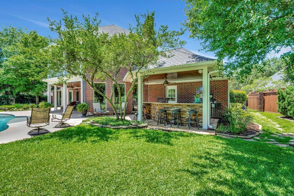 This photo showcases a spacious, upstairs covered balcony with a wood-paneled ceiling and ceiling fans, overlooking a serene water view and lush greenery, perfect for enjoying morning coffee, reading your favorite book or just relaxing.
