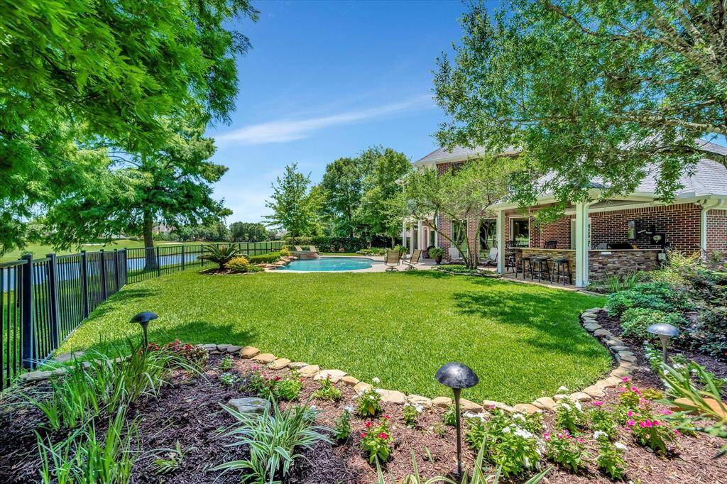 This property features a spacious home with a large backyard, complete with a swimming pool and hot tub, overlooking a serene pond on Bay Oaks Golf course #5.  Surrounded by lush greenery, it offers privacy and a picturesque setting.
