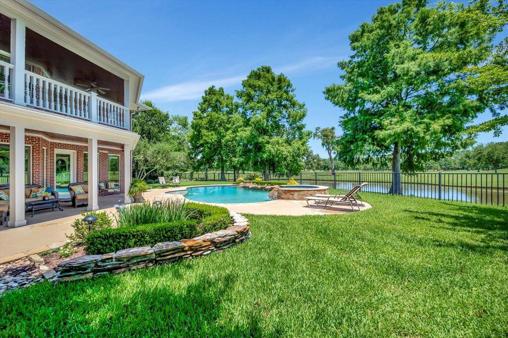This photo showcases a beautiful golf course property with a spacious backyard, mature trees, and a swimming pool. The house is nestled in a lush, green setting, offering serene water views and ample outdoor space .