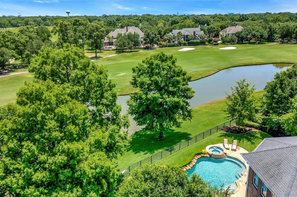 This photo showcases a scenic view from a home, featuring a spacious backyard with a pool and spa, overlooking a golf course with lush greenery and a pond. Ideal for golf enthusiasts and nature lovers.