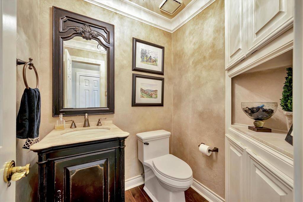 Powder room conveniently located near dining room, family room and kitchen. Warm neutral colors. Built-in shelving and framed mirror.