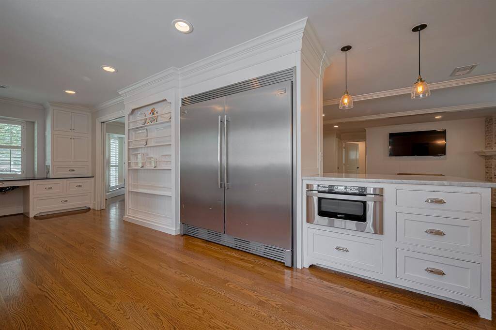 KITCHEN - Oversized stainless fridge and a built in microwave in the peninsula island with room for seating.