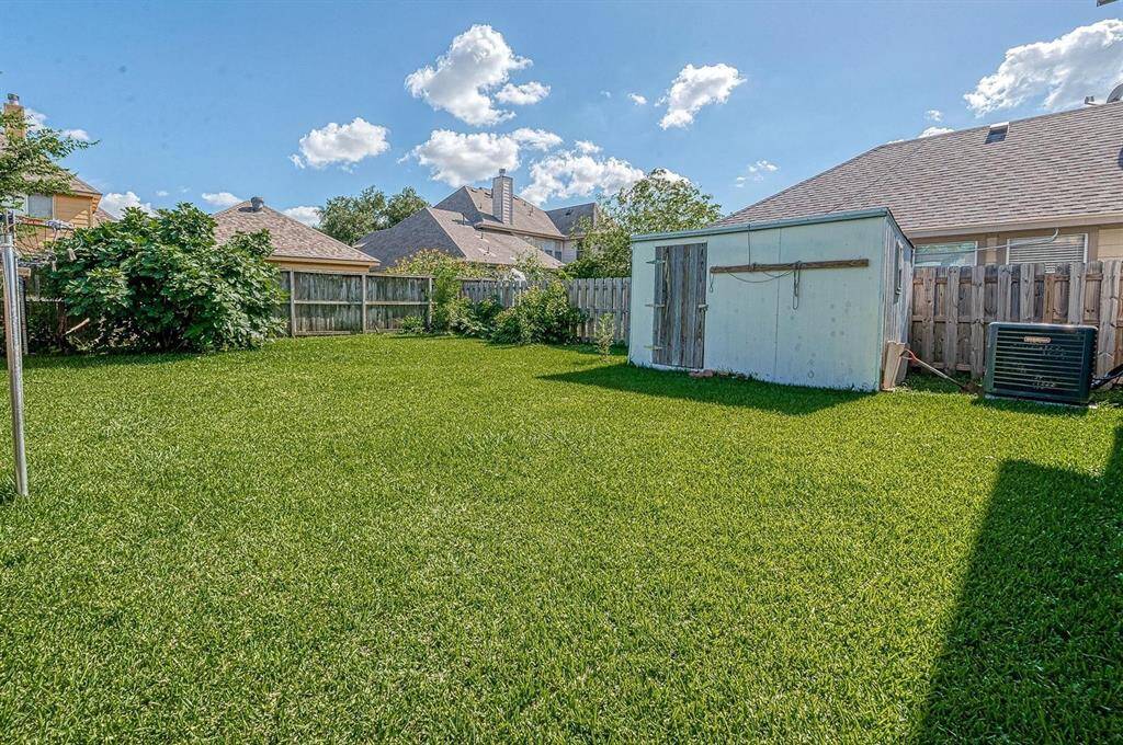 Spacious backyard with well-maintained lawn, a small shed, and wooden fencing, offering privacy and ample room for outdoor activities.