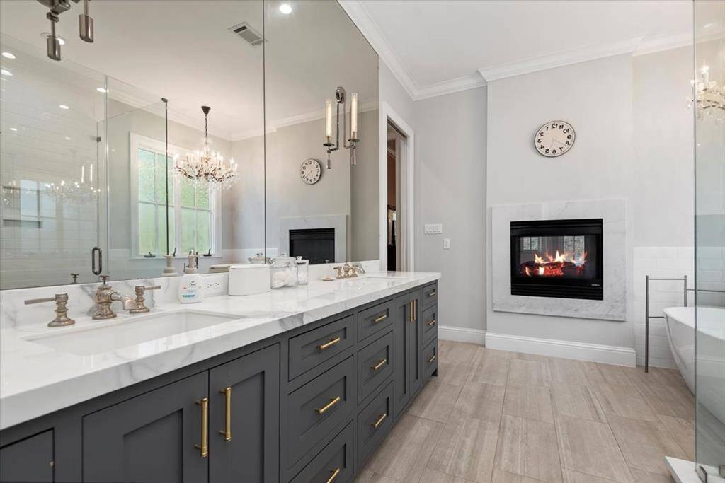 This bathroom features a sleek vanity with a granite countertop, stylish sink, and a modern black-framed mirror. Warm lighting and a subtle towel ring add to its cozy appeal.