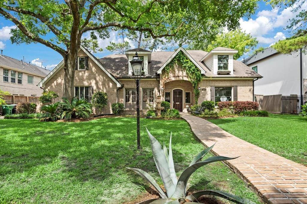 Charming brick home with lush landscaping, featuring a curved walkway leading to an inviting entrance. Mature trees provide shade, and a beautiful lamp post adds character to the front yard. Ideal for those seeking a picturesque, welcoming exterior.