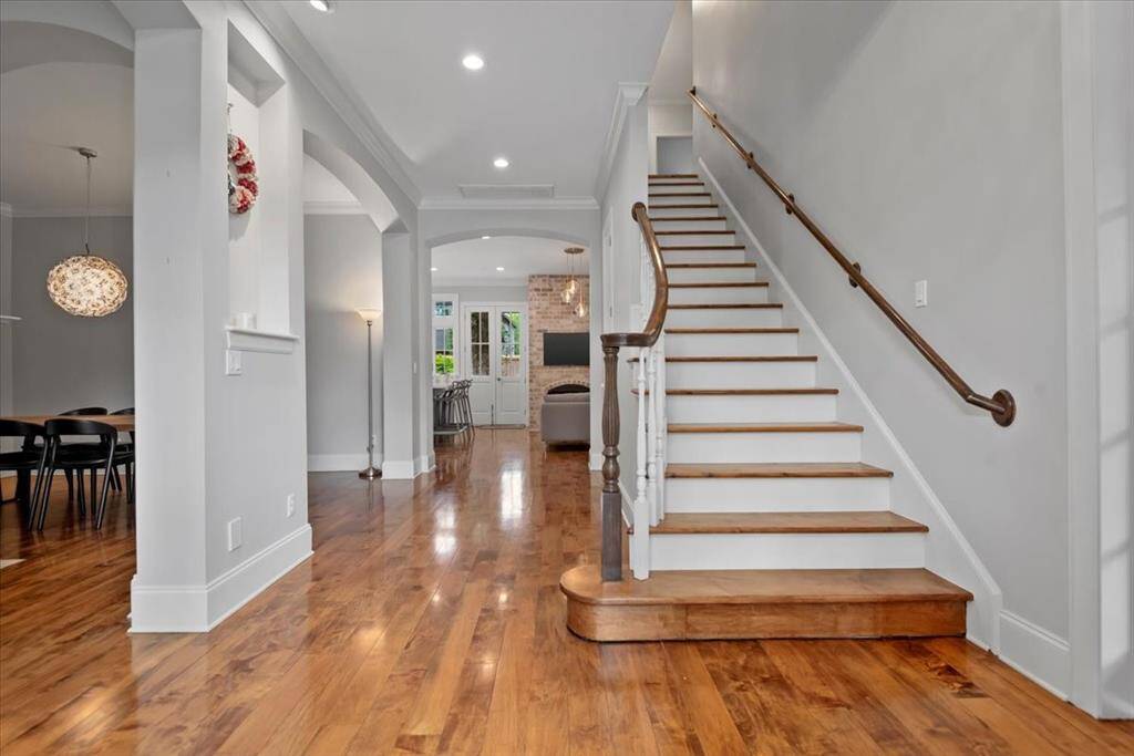 This photo showcases an inviting home interior with polished hardwood floors, an elegant staircase, and an open layout.