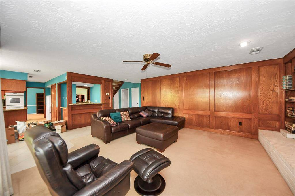 Family room with a fireplace and wood panels, overlooking backyard.