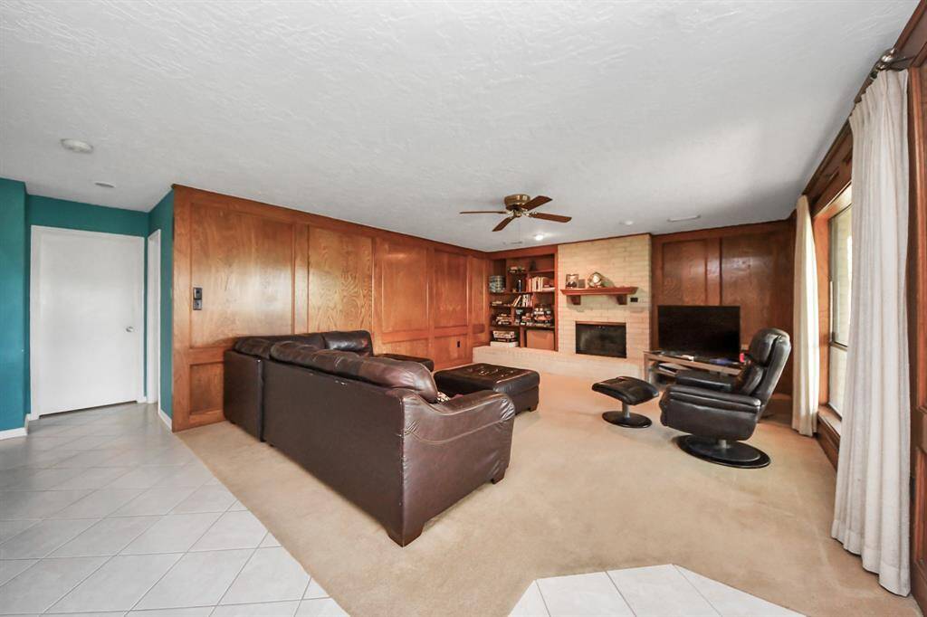 Family room with a fireplace and wood panels, overlooking backyard.