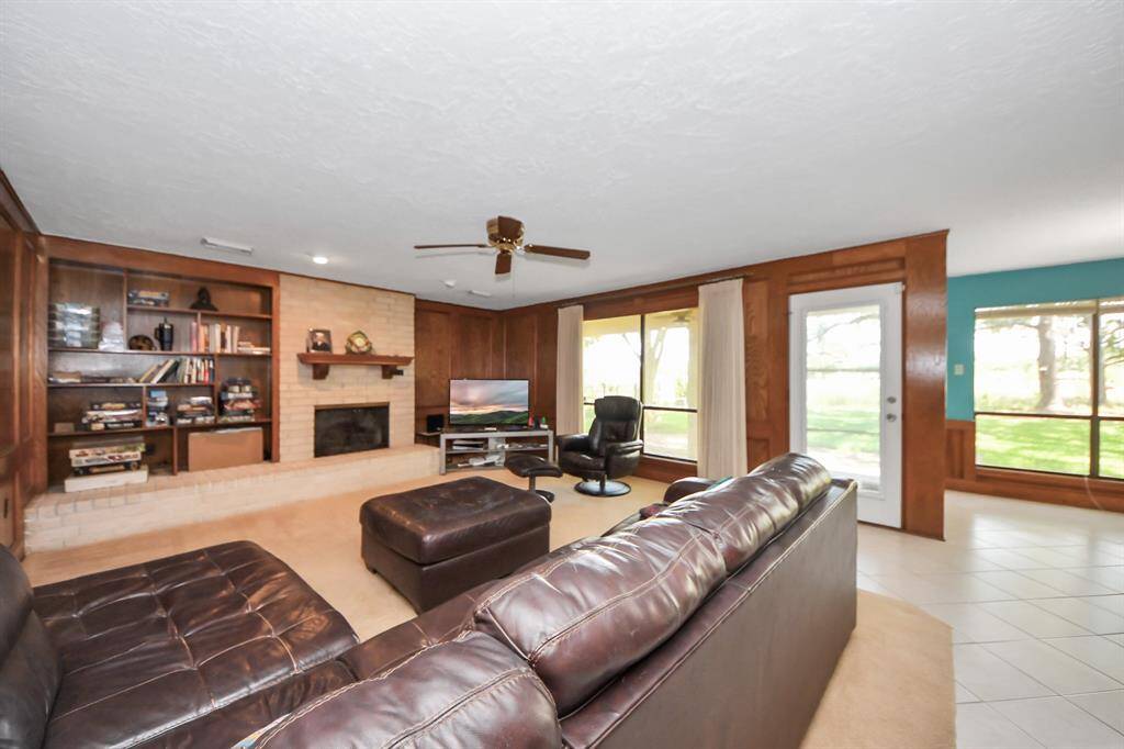 Family room with a fireplace and wood panels, overlooking backyard.