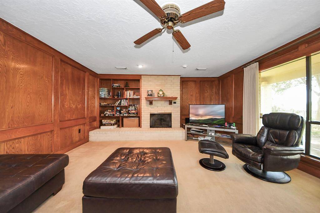 Family room with a fireplace and wood panels, overlooking backyard.