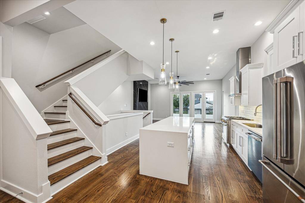 A beautifully designed kitchen flows effortlessly into the main living areas, while the nearby staircase adds architectural interest. The layout emphasizes openness and functionality, perfect for modern living.