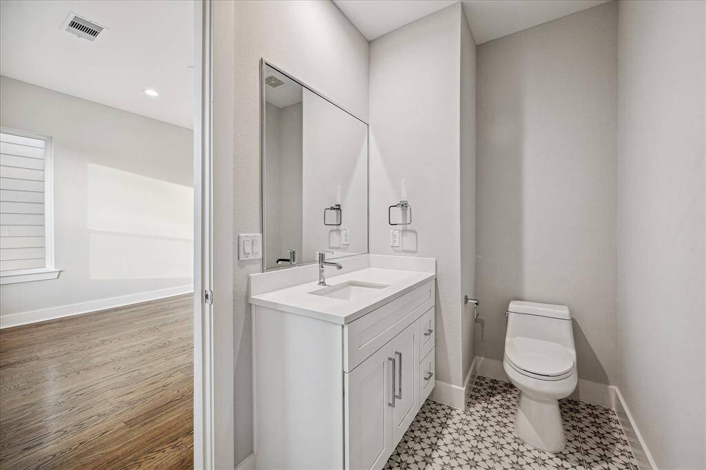This sleek powder room combines modern fixtures with eye-catching patterned tile flooring, providing both style and functionality. A perfect blend of elegance and utility, conveniently located near the main living areas.