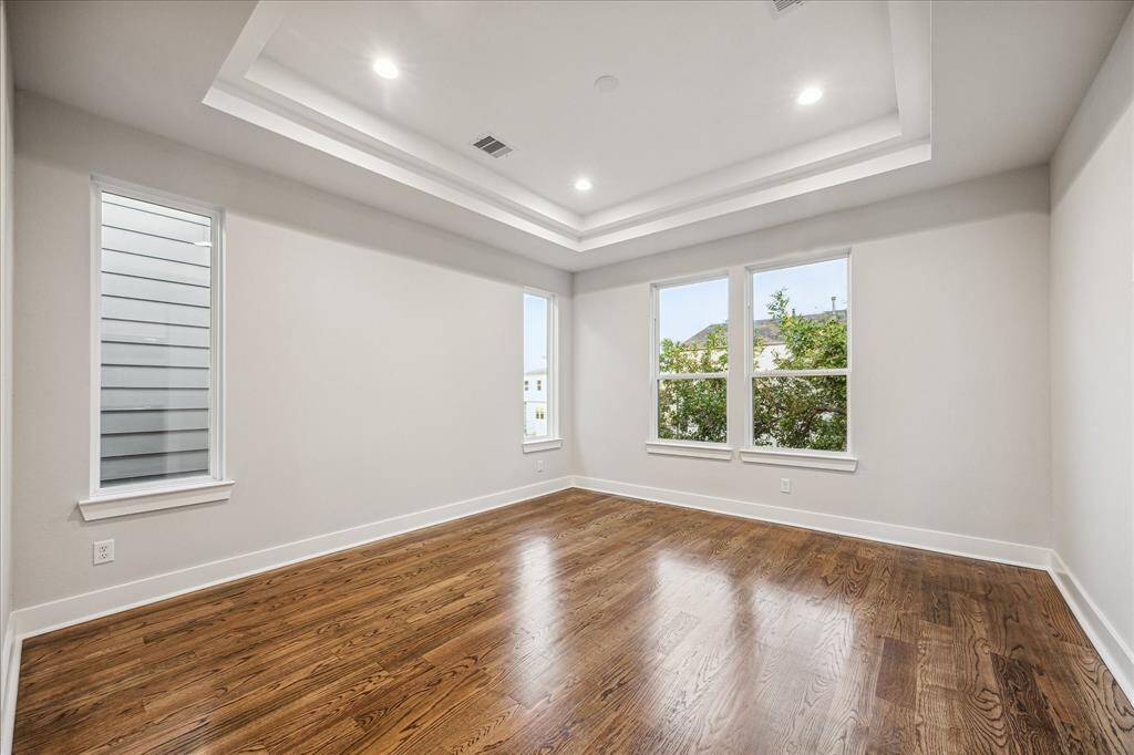 The primary suite is a true sanctuary, showcasing tray ceilings and large windows that fill the space with natural light. This spacious bedroom offers modern decor making it a luxurious retreat within the home. Ideal for those who appreciate a blend of elegance and comfort.