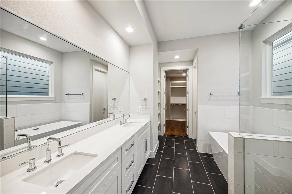 This bathroom is designed with elegance in mind, featuring highend finishes, a double vanity and sleek, black-tiled flooring. The spacious layout includes a luxurious soaking tub and a walk-in shower, providing the ultimate spa-like experience in the comfort of your home.