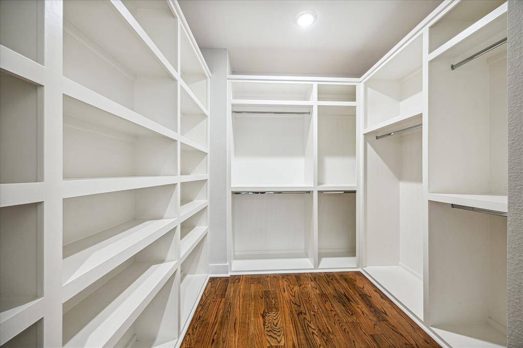 This large walk-in closet provides plenty of storage with built-in shelves and hanging space. The bright, clean design is ideal for organizing and accessing wardrobe essentials, making it a stylish and practical addition to the home.