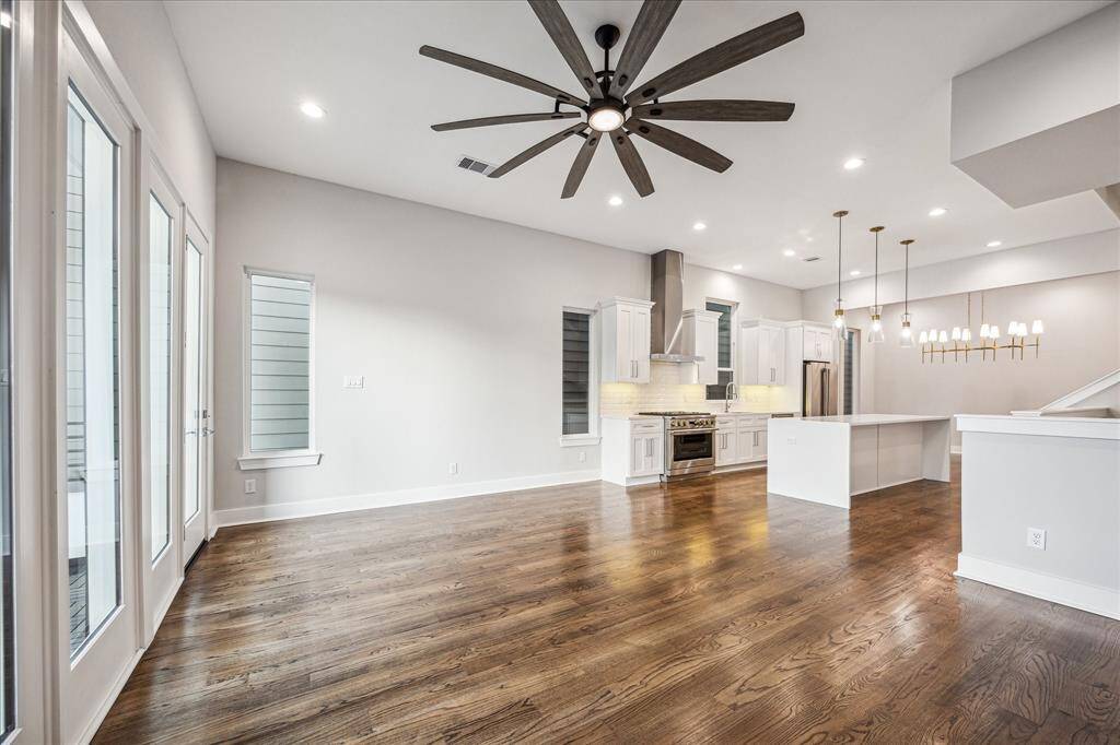 Host in style with a spacious living area centered around a sleek black marble fireplace wall. The ceiling fan, recessed lights, and open concept layout connect effortlessly to the dining and kitchen.