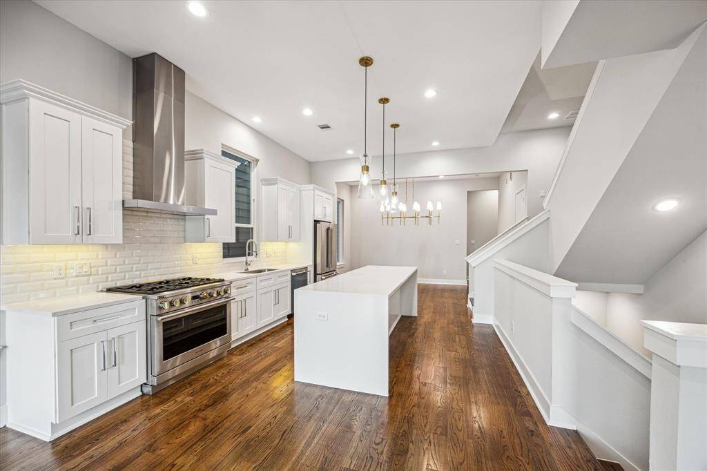 This jaw-dropping kitchen features custom cabinetry, a premium gas range, stainless steel appliances, and a stunning kitchen island. Gold pendant lighting adds sophistication to a space designed for cooking and gathering.