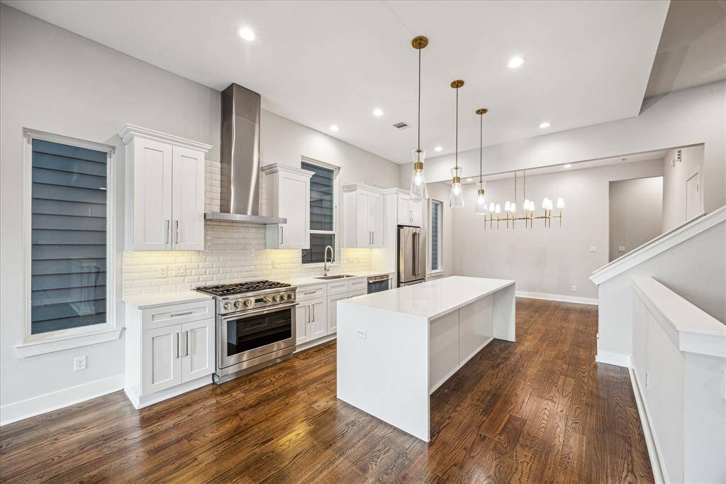 At the heart of this kitchen is a large island ideal for meal prep and socializing. The stainless steel cooking range and hood, set against a subway tile backsplash, combine practicality with sophisticated design. This kitchen is a functional and stylish space for anyone who loves to cook or entertain.