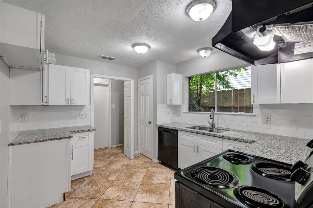 The kitchen features sleek granite countertops and a window above the double sinks that brings in natural light. The open door leads directly to the laundry area and garage for added convenience.