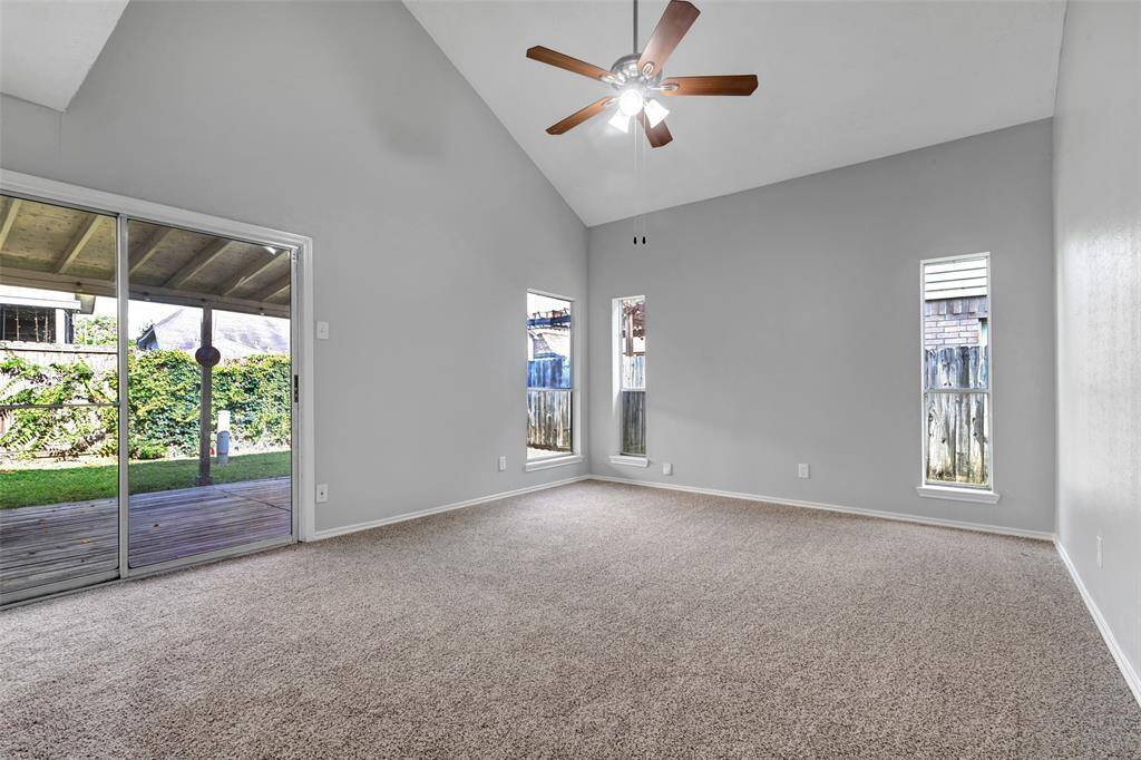 The primary bedroom features carpeted flooring and sliding glass doors that open to the backyard. Large windows let in plenty of natural light, making the space bright and inviting.