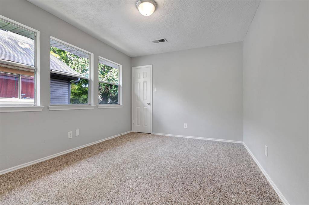 The middle bedroom on the second floor features three large glass windows that fill the space with natural light. That closed door leads to a walk-in closet, providing plenty of storage.